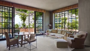 A photo of the naturally lit tribeca penthouse drawing room/seating area with table and chairs, glass doors that open to the balcony and a comfy sofa and chair