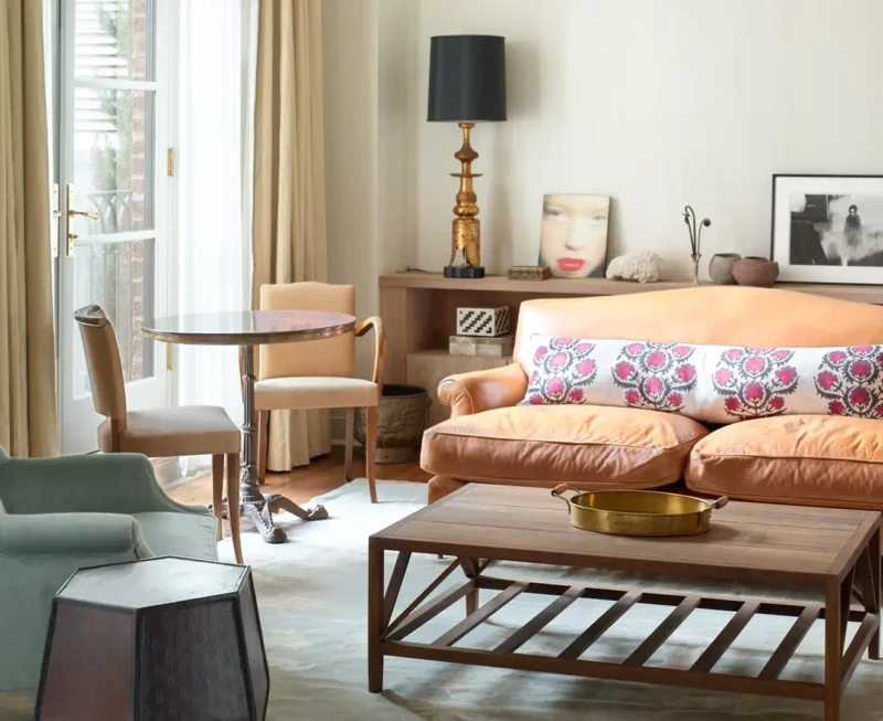 Two Bedroom Studio Suite Seating area featuring an armchair, sofa, coffee table, lamps and decor and large window with natural light.