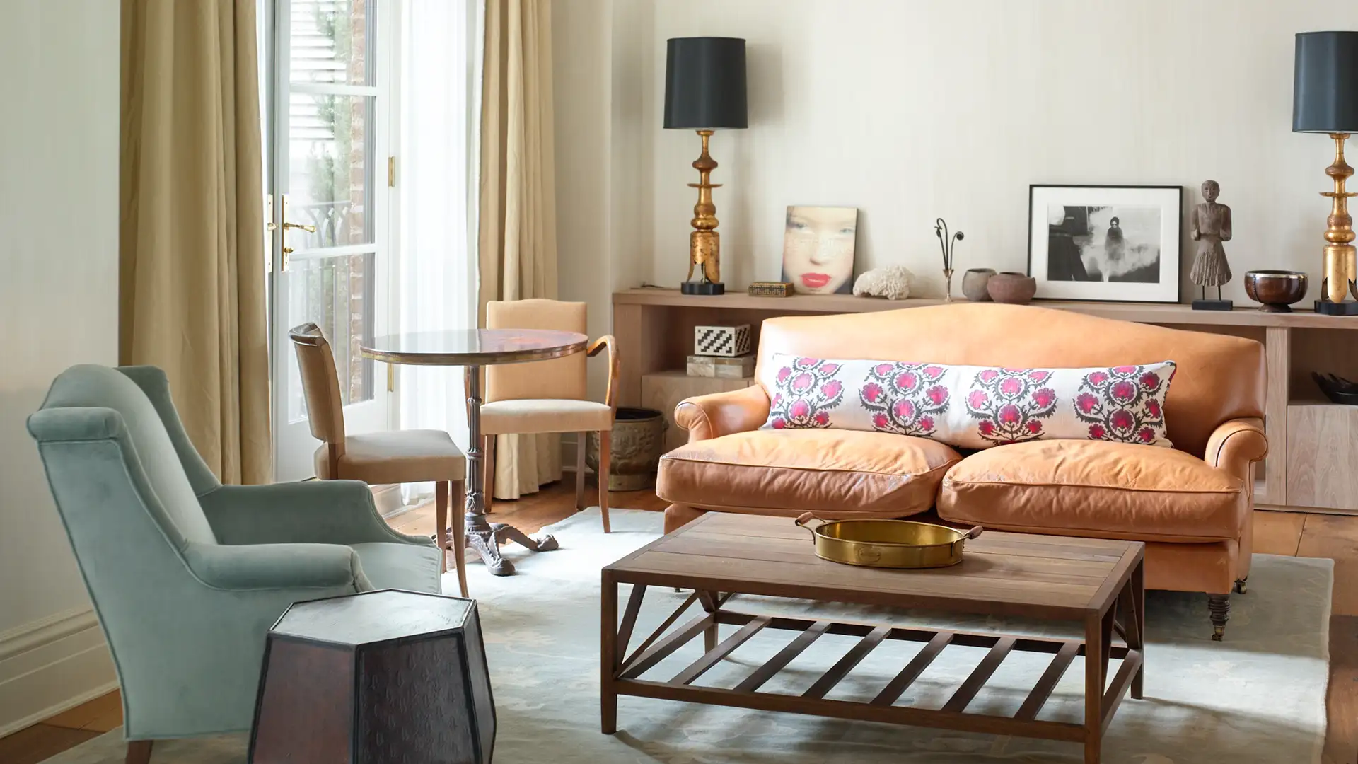 Two Bedroom Studio Suite Seating area featuring an armchair, sofa, coffee table, lamps and decor and large window with natural light.